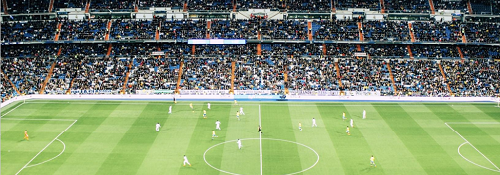 A football match taking place in a huge stadium with the stands full of spectators